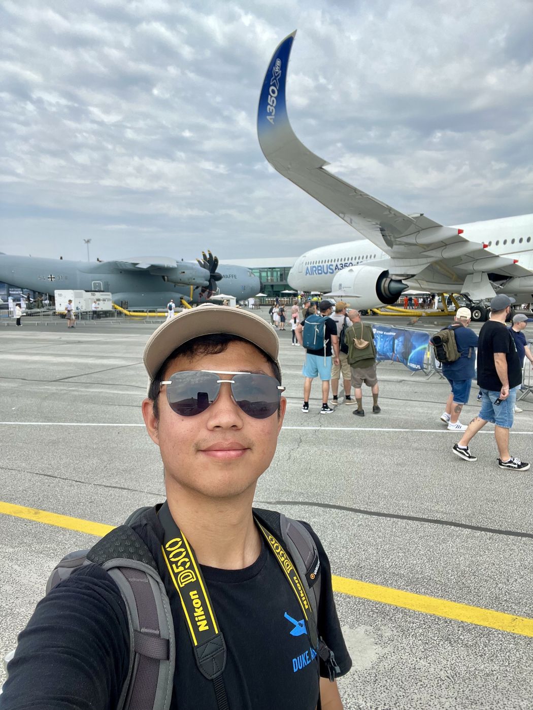 Selfie of Thomas on an air show ramp, with an Airbus A350 and a military transport aircraft behind