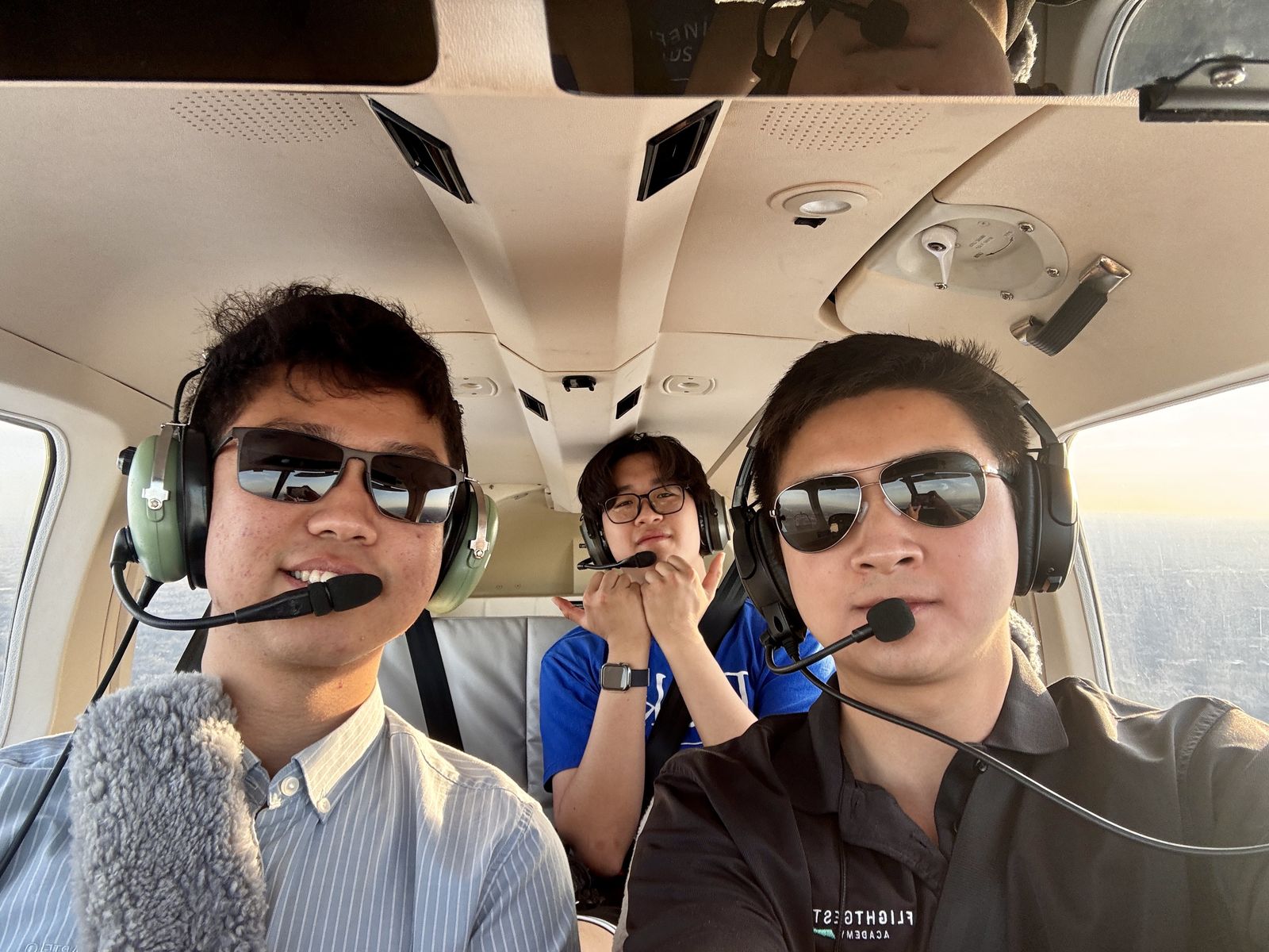 Three people wearing aviation headsets inside a small aircraft cockpit
